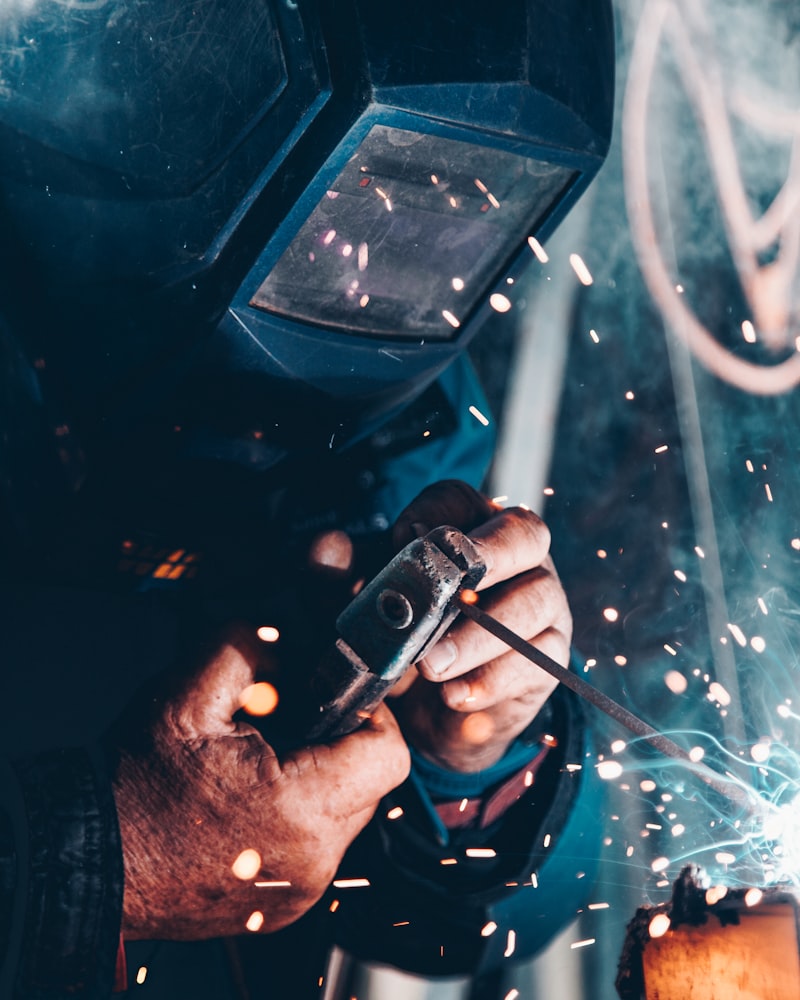 A welder in a face shield working through a shower of sparks in the welding bay